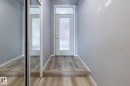 The entry features light-colored wood flooring, a white door with a frosted glass panel, and a mirrored closet door - 210 10147 112 Street, Edmonton, AB  - Indoor Photo Showing Other Room 