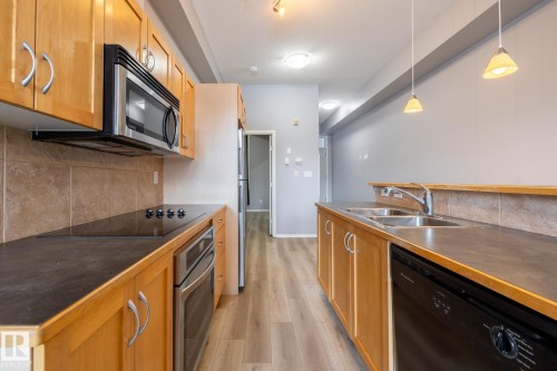 Kitchen featuring light wood cabinetry, stainless steel appliances, and a double basin sink - 210 10147 112 Street, Edmonton, AB - Indoor Photo Showing Kitchen With Double Sink
