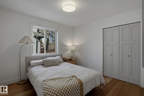 Bedroom featuring hardwood floors, a window offering views of trees, and a closet with bifold doors - 9228 100 Avenue, Edmonton, AB - Indoor Photo Showing Bedroom