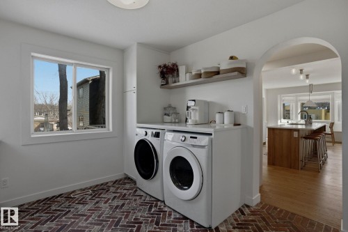 Laundry area featuring a large window, brick-patterned flooring, and a countertop with open shelving - 9228 100 Avenue, Edmonton, AB - Indoor Photo Showing Laundry Room