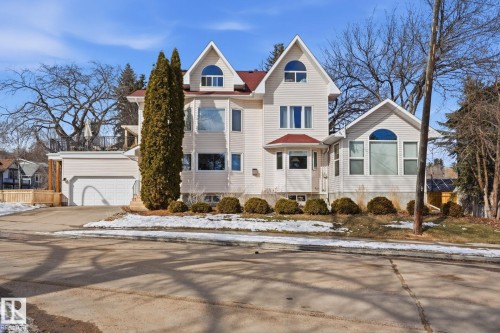The property features a light-colored exterior with a red roof, multiple gabled sections, and arched windows - 9228 100 Avenue, Edmonton, AB - Outdoor With Facade