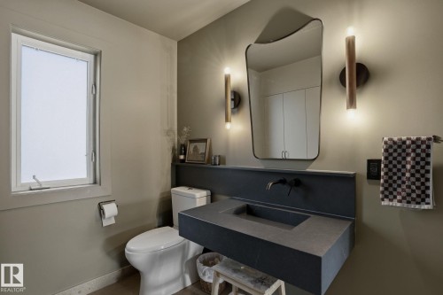 The bathroom features a floating vanity with an integrated sink, a wall-mounted faucet, and a contemporary mirror - 9228 100 Avenue, Edmonton, AB - Indoor Photo Showing Bathroom