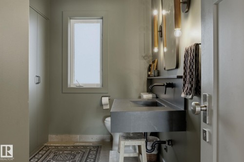 This well-appointed bathroom features a contemporary floating vanity with an integrated sink and wall-mounted faucet, complemented by modern wall sconces - 9228 100 Avenue, Edmonton, AB - Indoor Photo Showing Bathroom