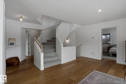 Entryway featuring hardwood floors, a carpeted staircase with a light wood handrail, and white walls - 9228 100 Avenue, Edmonton, AB - Indoor Photo Showing Other Room