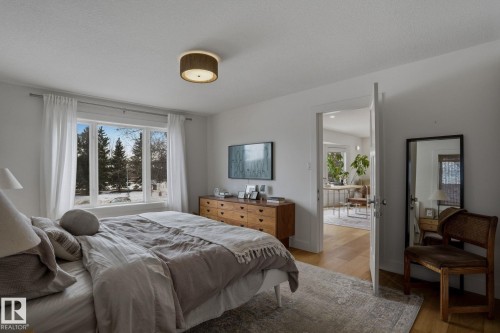 This room features a large window with a view of snow-covered trees, hardwood flooring, and a ceiling-mounted light fixture - 9228 100 Avenue, Edmonton, AB - Indoor Photo Showing Bedroom