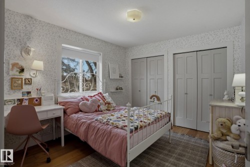 This room features hardwood floors, a window with an exterior view, and two closet doors - 9228 100 Avenue, Edmonton, AB - Indoor Photo Showing Bedroom