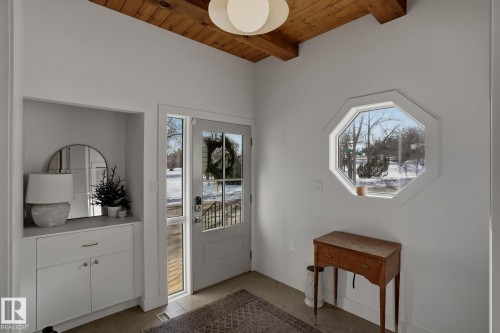 Welcoming entryway featuring a wood beam ceiling, a front door with glass panels, and an octagonal window providing exterior views - 9228 100 Avenue, Edmonton, AB - Indoor Photo Showing Other Room