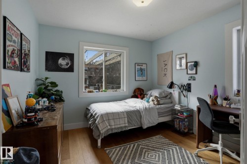 This room features light blue walls, a window providing natural light, and hardwood flooring - 9228 100 Avenue, Edmonton, AB - Indoor Photo Showing Bedroom