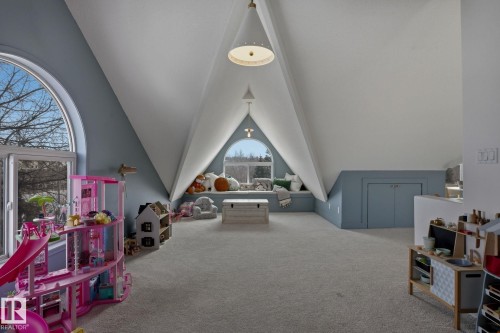 This spacious room features vaulted ceilings, arched windows, and soft gray carpeting - 9228 100 Avenue, Edmonton, AB - Indoor Photo Showing Other Room