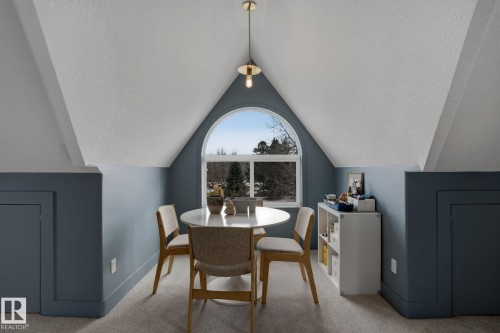 This versatile room features a large arched window providing natural light, sloped ceilings, and built-in storage on both sides - 9228 100 Avenue, Edmonton, AB - Indoor Photo Showing Dining Room