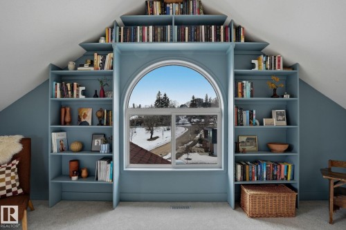 This space features built-in shelving units with a soft blue finish, encompassing a large arched window - 9228 100 Avenue, Edmonton, AB - Indoor