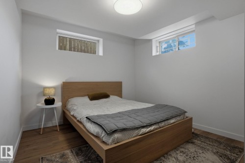 This room features light-toned wood flooring, light-colored walls, and a light-colored ceiling with a central light fixture - 9228 100 Avenue, Edmonton, AB - Indoor Photo Showing Bedroom