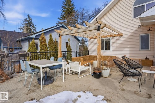 The property features an expansive concrete patio, complete with a rustic wooden pergola overhead - 9228 100 Avenue, Edmonton, AB - Outdoor With Deck Patio Veranda With Exterior