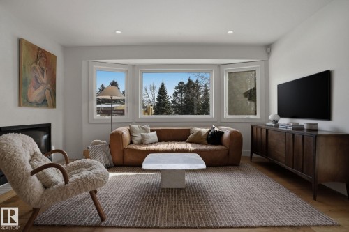 Living area featuring hardwood flooring, a fireplace, and a bay window providing views of the outdoors - 9228 100 Avenue, Edmonton, AB - Indoor Photo Showing Living Room