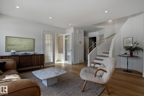 Living room featuring hardwood floors, recessed lighting, and a white staircase with a wooden handrail - 9228 100 Avenue, Edmonton, AB - Indoor Photo Showing Living Room