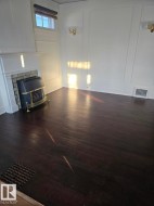 Unfurnished living room with a decorative wall, dark wood-style flooring, and a fireplace - 