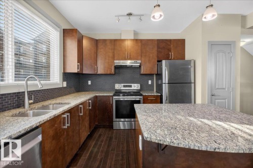 The kitchen features wood cabinetry, stainless steel appliances, and granite countertops - 2105 Casselman Link Link, Edmonton, AB - Indoor Photo Showing Kitchen With Stainless Steel Kitchen With Double Sink With Upgraded Kitchen