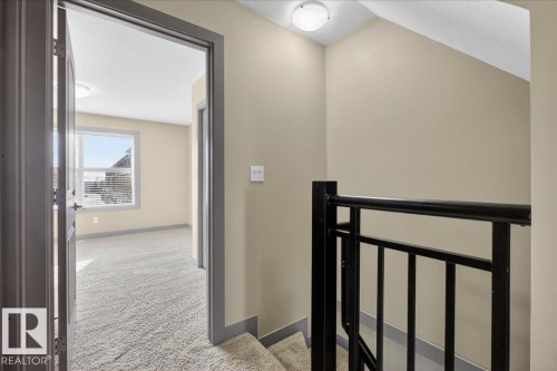 Interior view featuring light-colored walls, carpeted flooring, and a large window with blinds - 2105 Casselman Link Link, Edmonton, AB - Indoor Photo Showing Other Room