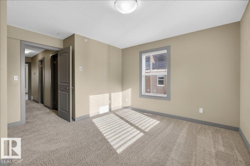 The room features neutral-toned walls, light-colored carpet, and a window with blinds - 2105 Casselman Link Link, Edmonton, AB - Indoor Photo Showing Other Room