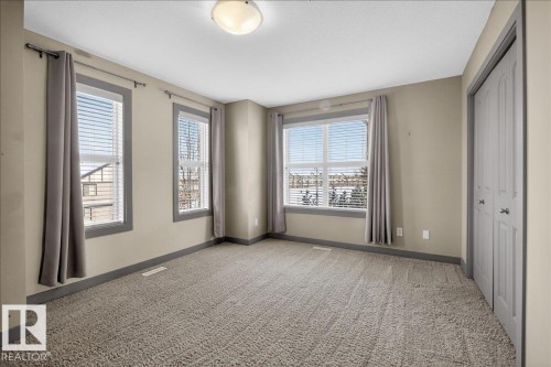 This room features light-colored walls, carpeted flooring, and a ceiling-mounted light fixture - 2105 Casselman Link Link, Edmonton, AB - Indoor Photo Showing Other Room