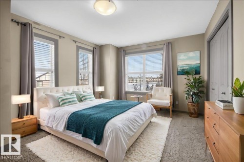 Bedroom featuring a white tufted bed frame, neutral-toned walls, and large windows with blinds - 2105 Casselman Link Link, Edmonton, AB - Indoor Photo Showing Bedroom