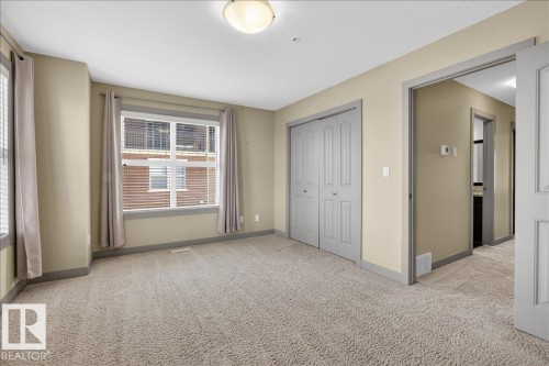 This room features neutral-toned carpeting, a window with blinds and curtains, and a bi-fold closet - 2105 Casselman Link Link, Edmonton, AB - Indoor Photo Showing Other Room