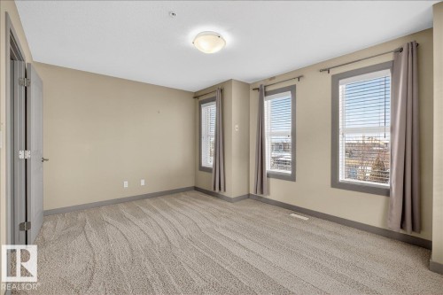 Well-appointed room featuring soft beige walls, a neutral patterned carpet, and three windows offering natural light - 2105 Casselman Link Link, Edmonton, AB - Indoor Photo Showing Other Room
