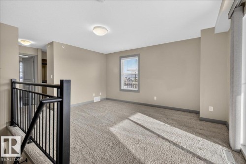 This spacious room features neutral-toned carpet, a window with blinds, and recessed lighting - 2105 Casselman Link Link, Edmonton, AB - Indoor Photo Showing Other Room