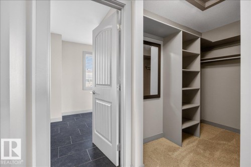 Walk-in closet featuring built-in shelving, hanging rods, and a framed mirror - 2105 Casselman Link Link, Edmonton, AB - Indoor