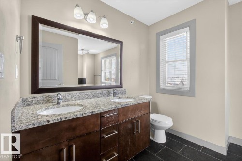 Bathroom featuring a double vanity with a granite countertop, dual sinks, and a large mirror - 2105 Casselman Link Link, Edmonton, AB - Indoor Photo Showing Bathroom