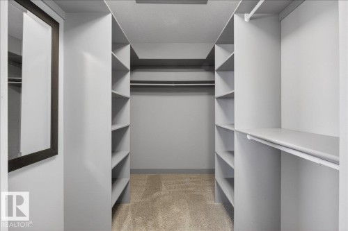 Walk-in closet featuring built-in shelving, hanging rods, and carpeting - 2105 Casselman Link Link, Edmonton, AB - Indoor With Storage
