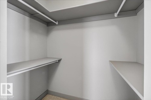 This closet features a neutral color palette, built-in shelving, and hanging rods for convenient storage - 2105 Casselman Link Link, Edmonton, AB - Indoor With Storage