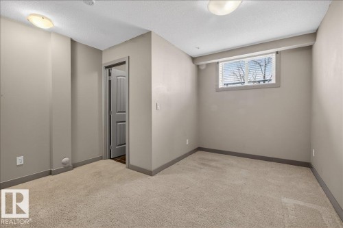 This room features light-colored carpet, neutral-toned walls, and a window with white blinds - 2105 Casselman Link Link, Edmonton, AB - Indoor Photo Showing Other Room