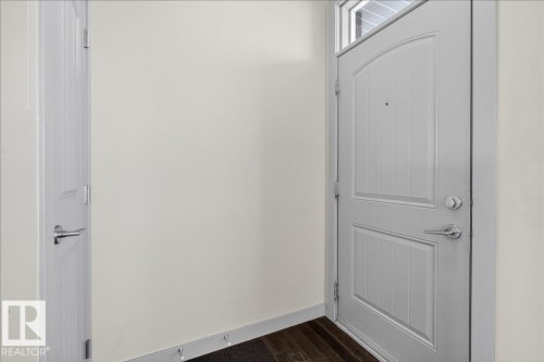 Entryway featuring a paneled door with a transom window, chrome hardware, and dark wood flooring - 2105 Casselman Link Link, Edmonton, AB - Indoor Photo Showing Other Room