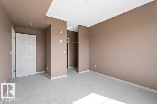 This room features light-colored carpeting, walls with a warm neutral tone, and white trim - 1-204 4245 139 Avenue, Edmonton, AB - Indoor Photo Showing Other Room