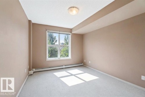 The room features a window providing natural light, a ceiling-mounted light fixture, and light-colored carpeting - 1-204 4245 139 Avenue, Edmonton, AB - Indoor Photo Showing Other Room