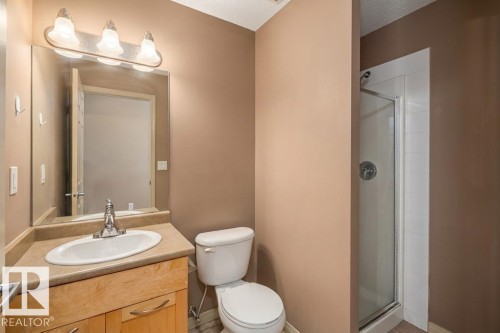 The bathroom features a light wood vanity with a light-colored countertop, a white sink, and a mirrored wall cabinet with overhead lighting - 1-204 4245 139 Avenue, Edmonton, AB - Indoor Photo Showing Bathroom