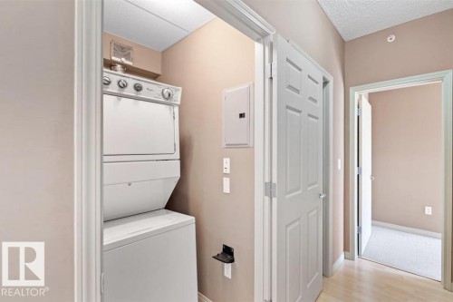 Dedicated laundry area featuring a white stacked washer and dryer unit - 1-204 4245 139 Avenue, Edmonton, AB - Indoor Photo Showing Laundry Room