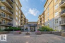 The property features a multi-story building with balconies, stone facade elements, and well-maintained landscaping with planters and shrubs - 1-204 4245 139 Avenue, Edmonton, AB  - Outdoor With Balcony 