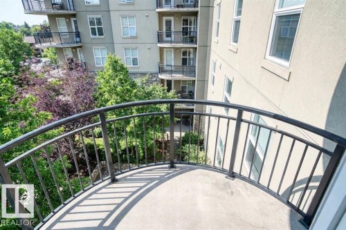 The property features a private balcony with a curved metal railing, offering views of surrounding trees and adjacent buildings - 1-204 4245 139 Avenue, Edmonton, AB - Outdoor With Balcony With Exterior
