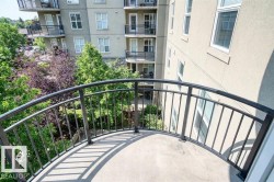 The property features a private balcony with a curved metal railing, offering views of surrounding trees and adjacent buildings - 