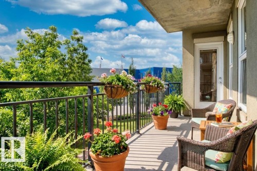 The property features a balcony with a dark metal railing and concrete flooring, offering an open-air extension of the living space - 1-204 4245 139 Avenue, Edmonton, AB - Outdoor With Deck Patio Veranda With Exterior