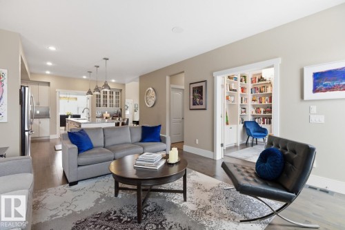 Features Gas Fireplace, Large West Facing Windows overlooking Manicured Backyard, Open to Kitchen Space, and Maple Hardwood Flooring - 7432 Colonel Mewburn Road, Edmonton, AB - Indoor Photo Showing Living Room