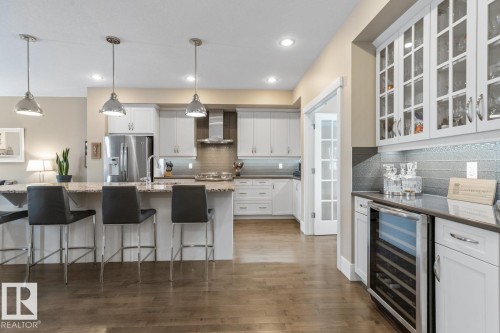 Open Concept Kitchen with Upgraded Granite Island Countertop, Gas Stove, Built in Microwave, Bar Space, Upgraded Cabinets (including Pots and Pans Drawers), and Maple Hardwood Flooring - 7432 Colonel Mewburn Road, Edmonton, AB - Indoor Photo Showing Kitchen With Upgraded Kitchen