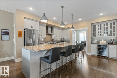 Open Concept Kitchen with Upgraded Granite Island Countertop, Gas Stove, Built in Microwave, Bar Space, Upgraded Cabinets (including Pots and Pans Drawers), and Maple Hardwood Flooring - 7432 Colonel Mewburn Road, Edmonton, AB - Indoor Photo Showing Kitchen With Upgraded Kitchen