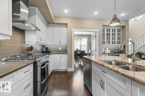Open Concept Kitchen with Upgraded Granite Island Countertop, Gas Stove, Built in Microwave, Bar Space, Upgraded Cabinets (including Pots and Pans Drawers), and Maple Hardwood Flooring - 7432 Colonel Mewburn Road, Edmonton, AB - Indoor Photo Showing Kitchen With Double Sink With Upgraded Kitchen