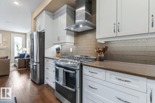Open Concept Kitchen with Upgraded Granite Island Countertop, Gas Stove, Built in Microwave, Bar Space, Upgraded Cabinets (including Pots and Pans Drawers), and Maple Hardwood Flooring - 7432 Colonel Mewburn Road, Edmonton, AB - Indoor Photo Showing Kitchen With Upgraded Kitchen