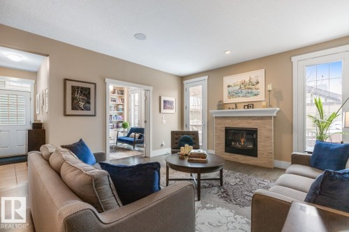 Features Gas Fireplace, Large West Facing Windows overlooking Manicured Backyard, Open to Kitchen Space, and Maple Hardwood Flooring - 7432 Colonel Mewburn Road, Edmonton, AB - Indoor Photo Showing Living Room With Fireplace