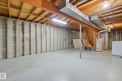 Unfinished below grade area featuring gas water heater, washer / dryer, and stairs - 