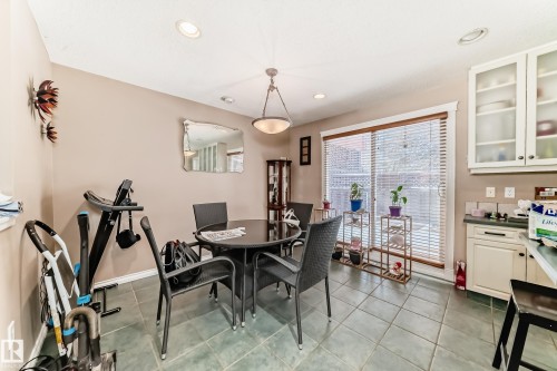 This bright dining area features tiled flooring, recessed lighting, and a sliding glass door with blinds providing access to the exterior - 597 Millbourne Road E, Edmonton, AB - Indoor Photo Showing Dining Room